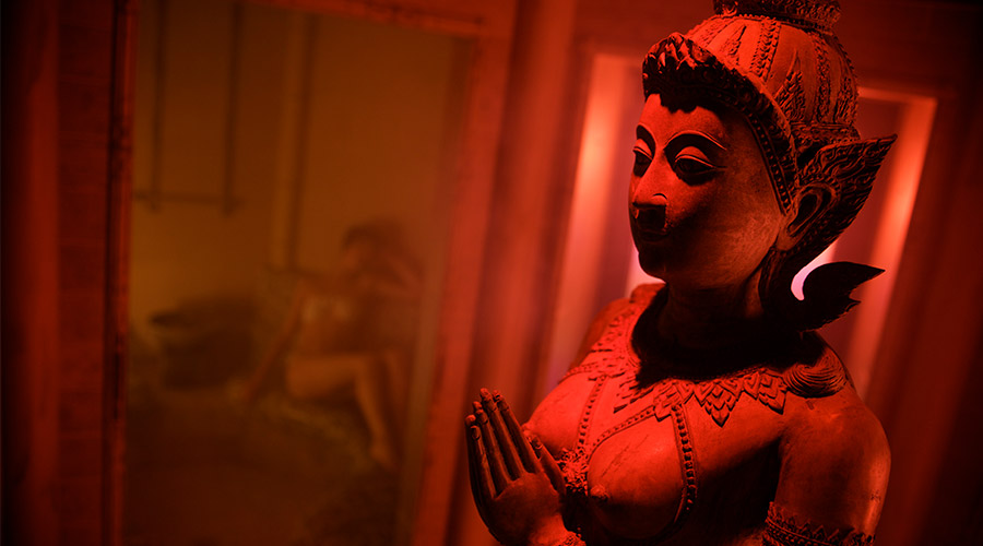 experience room with women in background sat in steam and statue in front of image