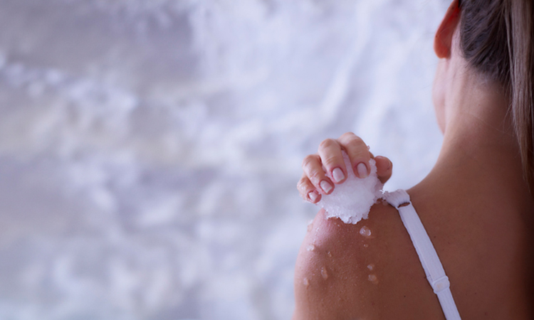 Woman rubbbing ice across her skin.