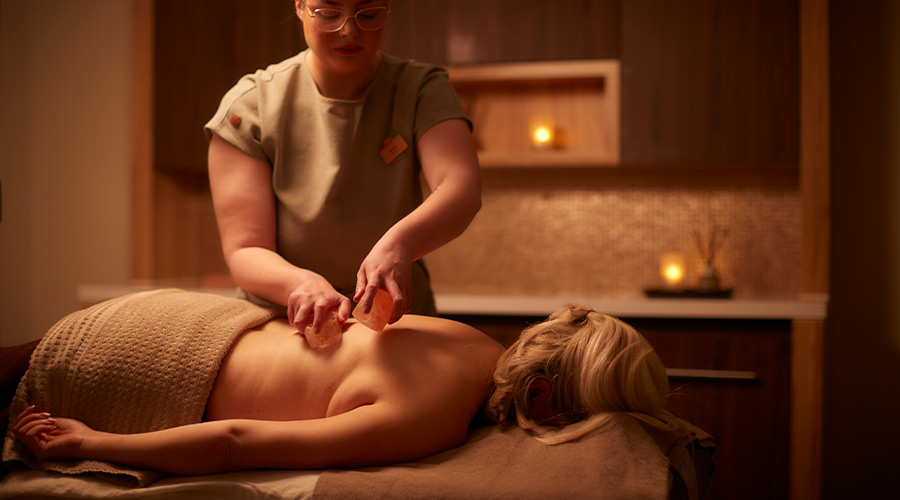 Woman having salt blocks placed on her back.
