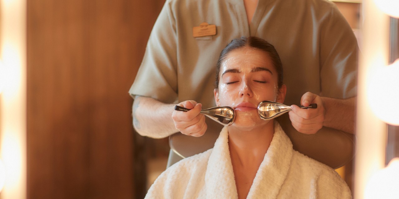 Woman having a facial with smooth metal discs.