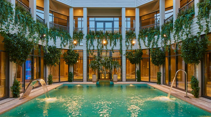 Outdoor courtyard pool with lots of hanging plants.