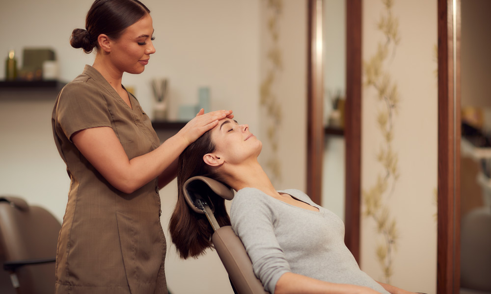 Woman having her head rubbed by a trained spa therapist.