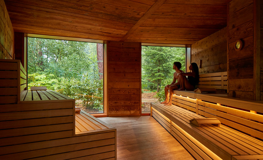 Couple sitting in the Nordic Sauna looking out at the forest.