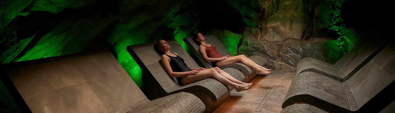 Two women sitting in the forest carvern.