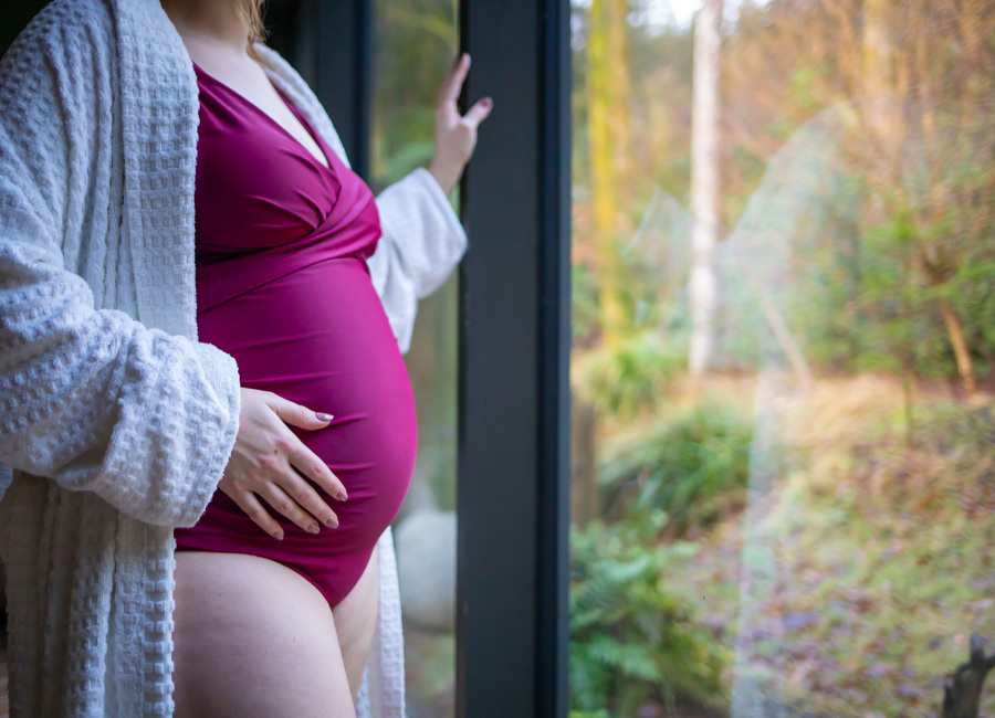 Pregnant woman looking out at the forest.