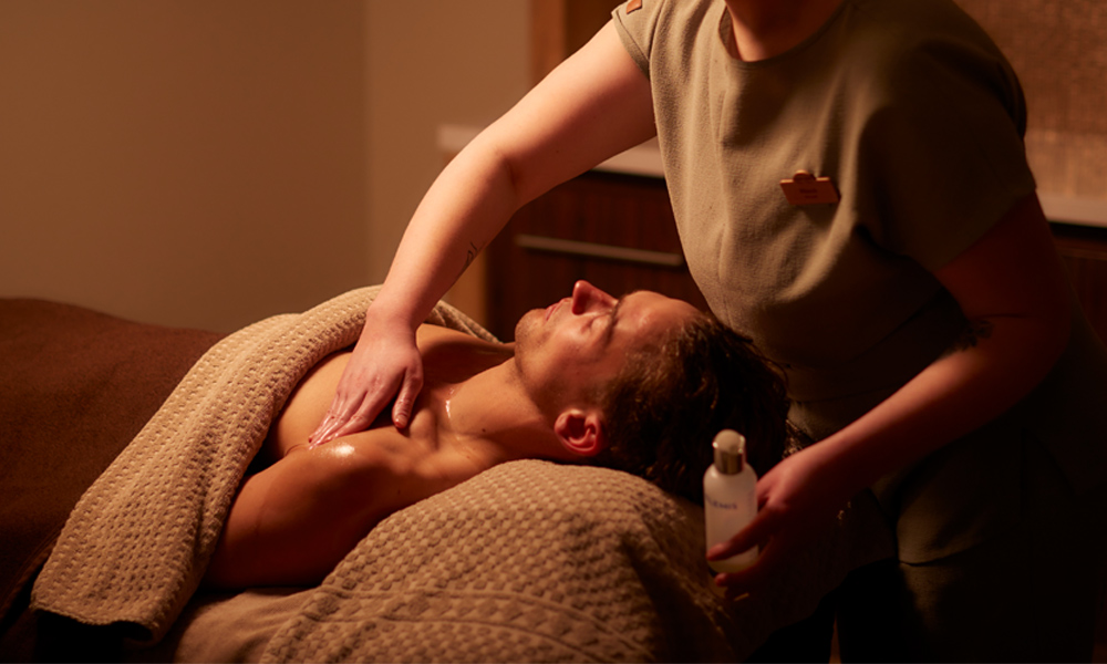 Woman applying products to a person laid in a treatment room.
