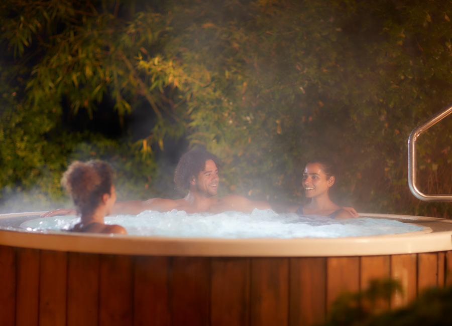 Group sitting in a bubbling outdoor hot tub.