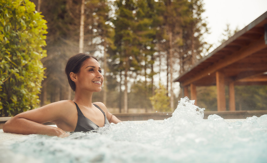 Woman soaking in a bubbling outdoor hot tub.