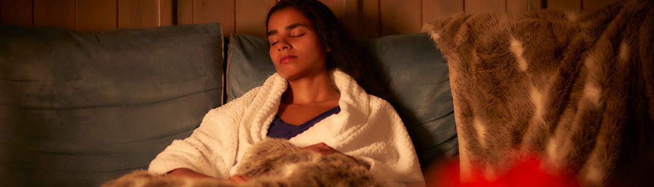Woman snuggled under a cosy blanket in the Scandinavian Snug.