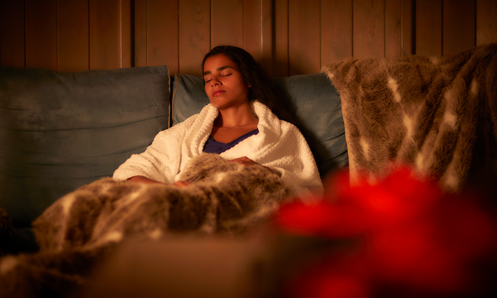 Woman snuggled under a cosy blanket in the Scandinavian Snug.