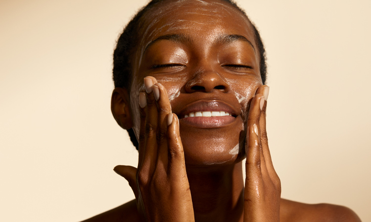 Woman smiling as she washes her face.