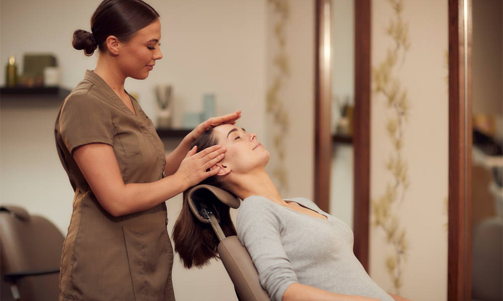 Woman laid back having her head touched.