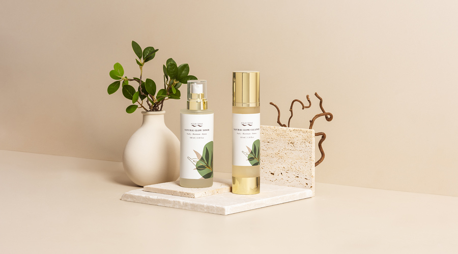 Aqua Sana natural glow products lined up with decorative foliage.