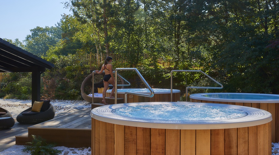 Woman stepping into a bubbling outdoor hot tub.