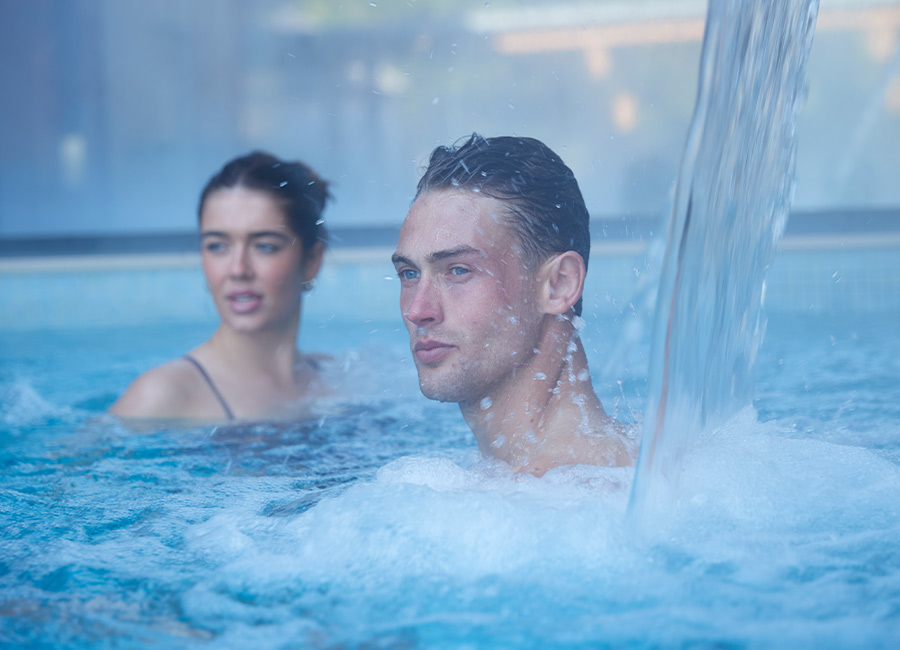 Man and woman soaking in an Outdoor Pool enjoying the forest view.