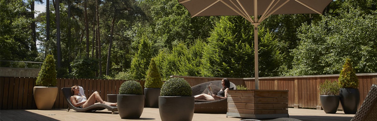 outdoor terrace in front of of forest with two ladies on loungers