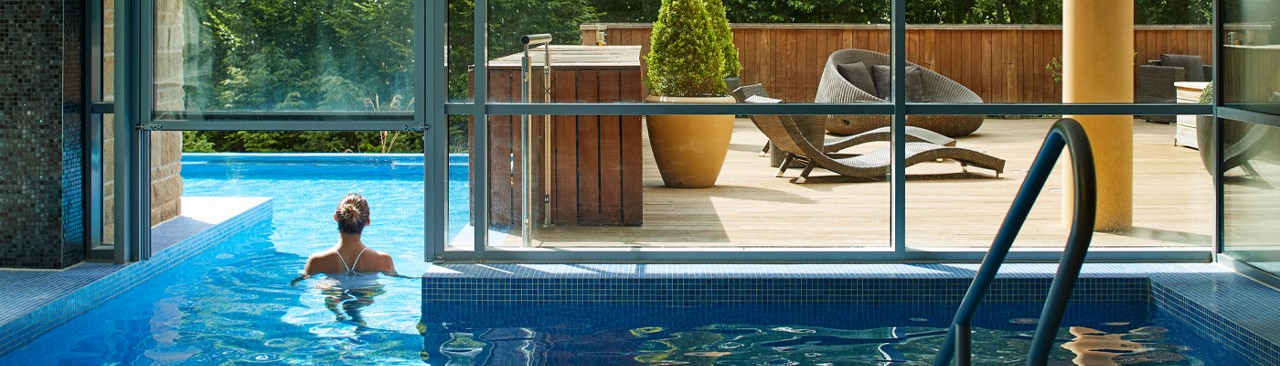 Woman soaking in a bubbling outdoor pool surrounded by the forest.