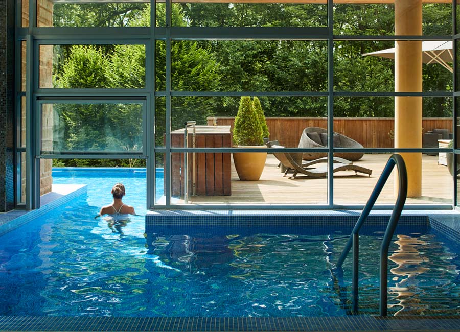 Woman soaking in an outdoor pool surrounded by the forest.