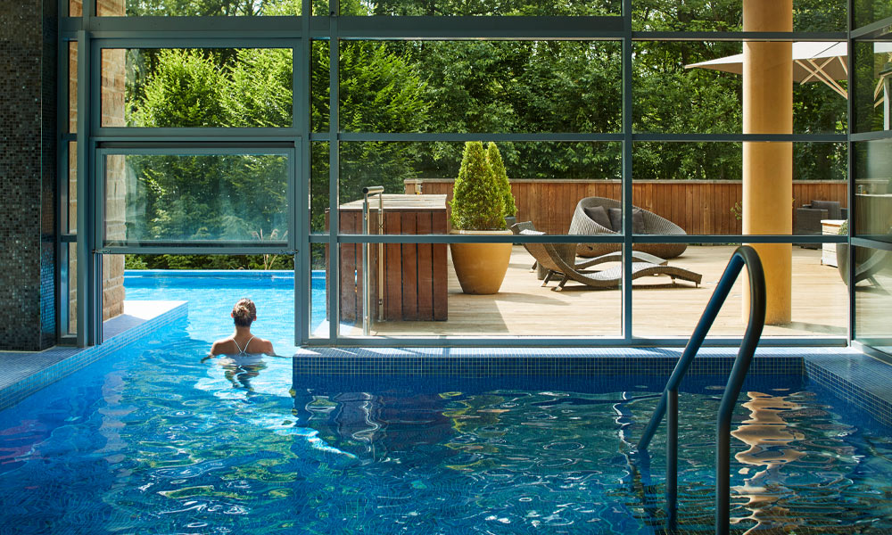 Woman soaking in an outdoor pool surrounded by the forest.