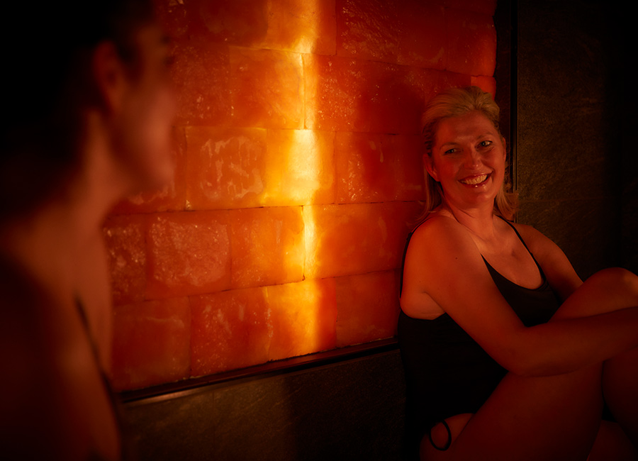 Two women inside a glowing Salt Steam Room.