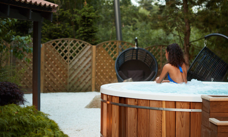 Woman looking out at the forest from a bubbling outdoor hot tub.