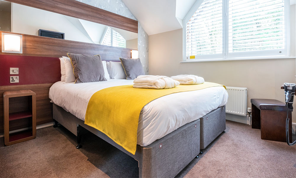 Inside our Spa Apartments with a bed, fresh flowers and views out to the surrounding forest.