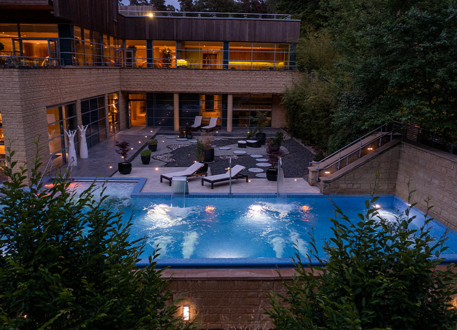 Outdoor pool in the evening with lounge seating. 