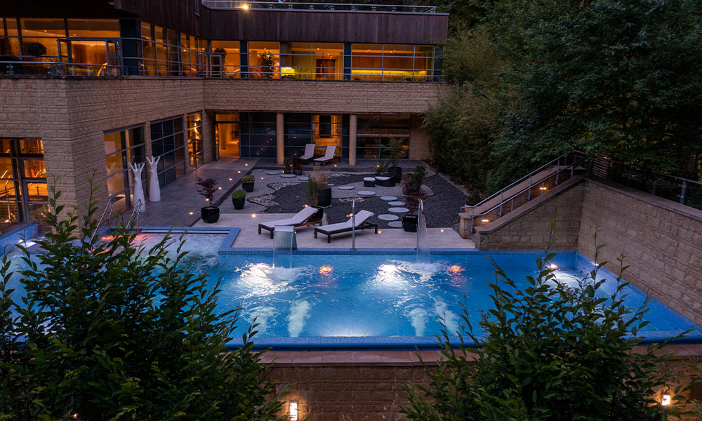 Outdoor pool in the evening, surrounded by the forest.
