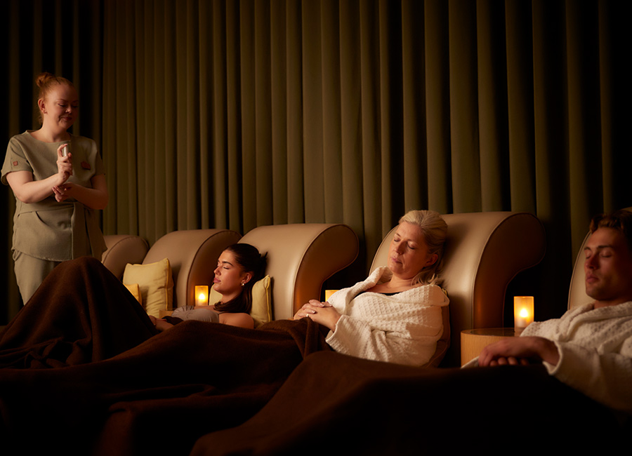 A group relaxing in a sleep session whilst a spa therapist sprays fragrance.