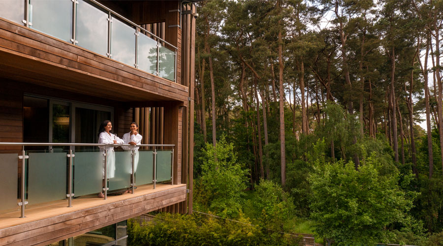 Mother and daughter standing on a balcony looking out to the forest.