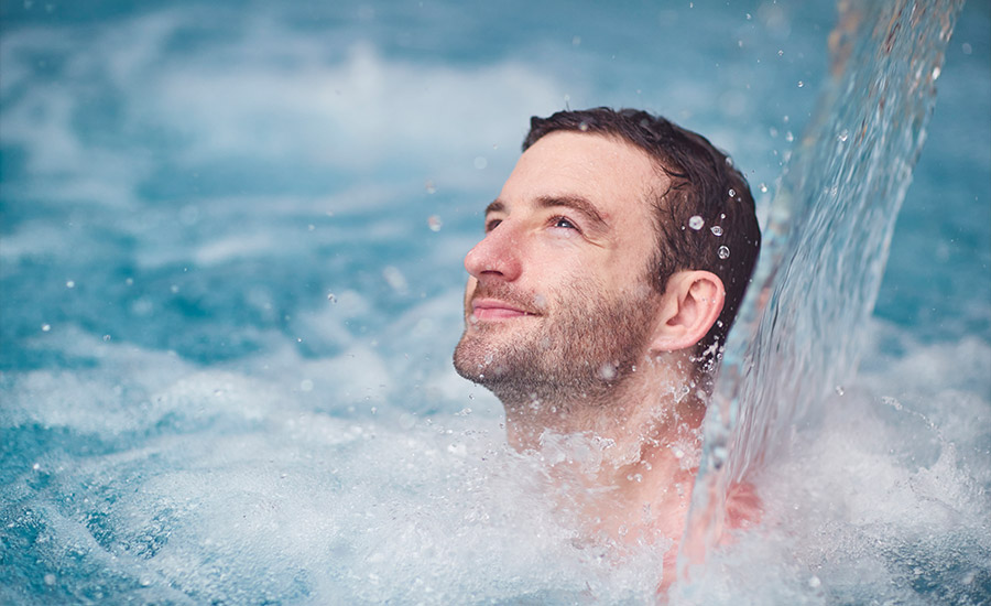 A man relaxing under a flowing water fountain.