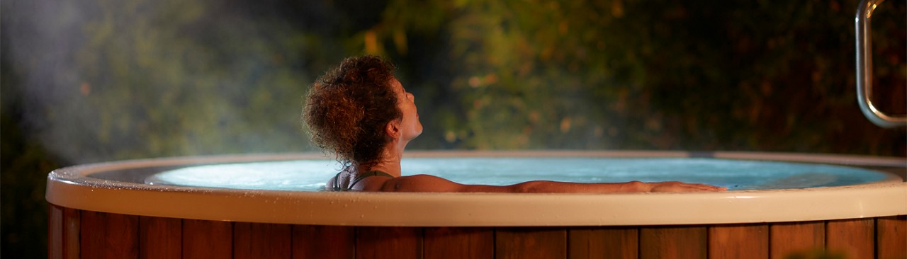 Woman soaking in a bubbling outdoor hot tub.