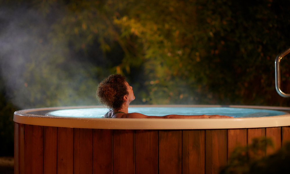 Woman soaking in a steamy outdoor hot tub.