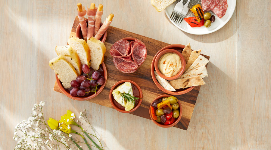 Grazing board with a selection of foods, including humous, breads and deli meats.