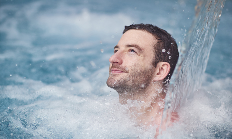 man in pool under water feature