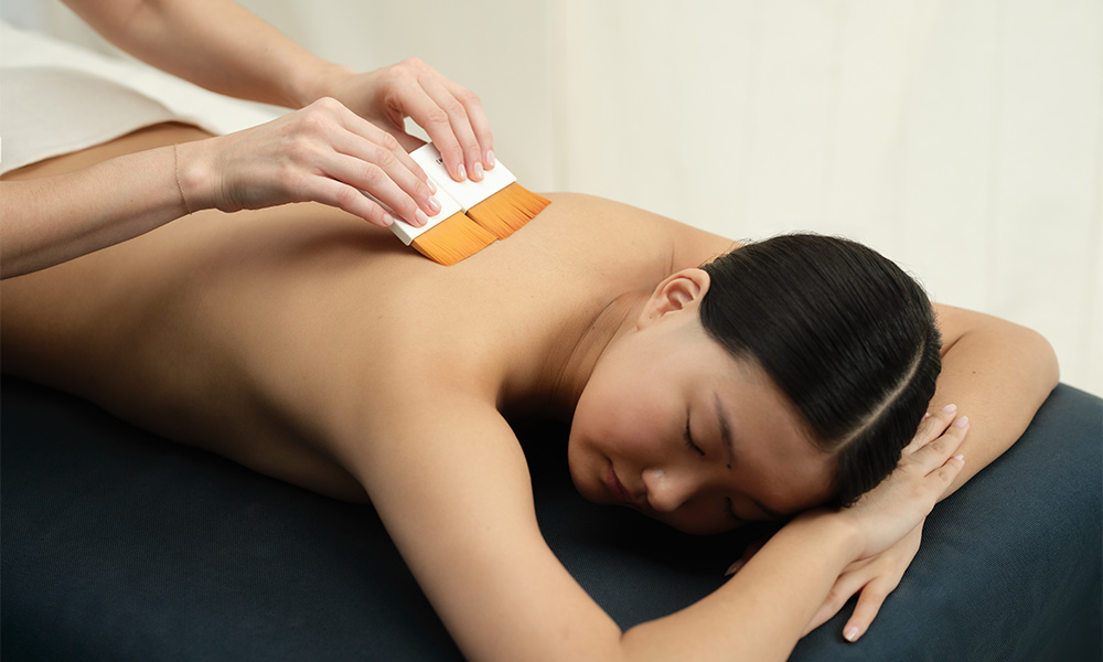 Woman having a back massage with body brushes.