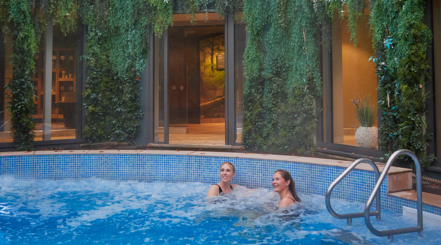Two women soaking in a bubbling outdoor pool.