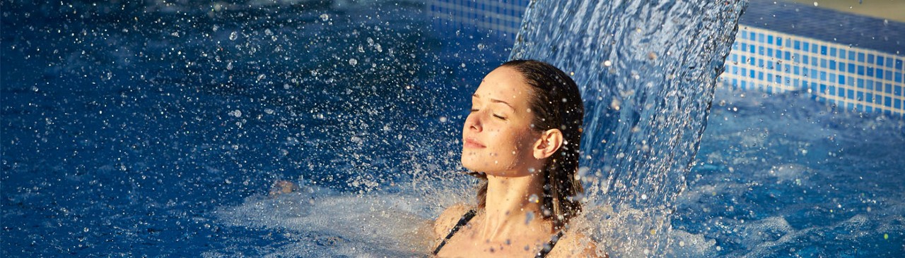 Women in pool next to water jet