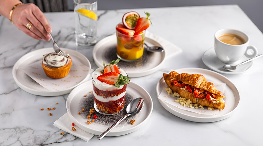 A selection of breakfast items, including yogurt and granola, fruit salad and a stuffed croissant. 