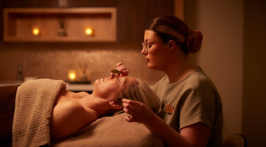 Woman laying in a treatment room as a therapist applied VOYA products.