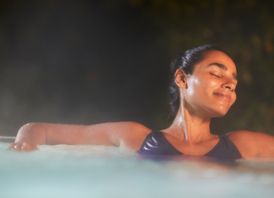 Woman soaking in a steamy outdoor hot tub.