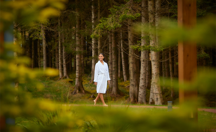 Woman walking through the forest in a fluffy spa robe.
